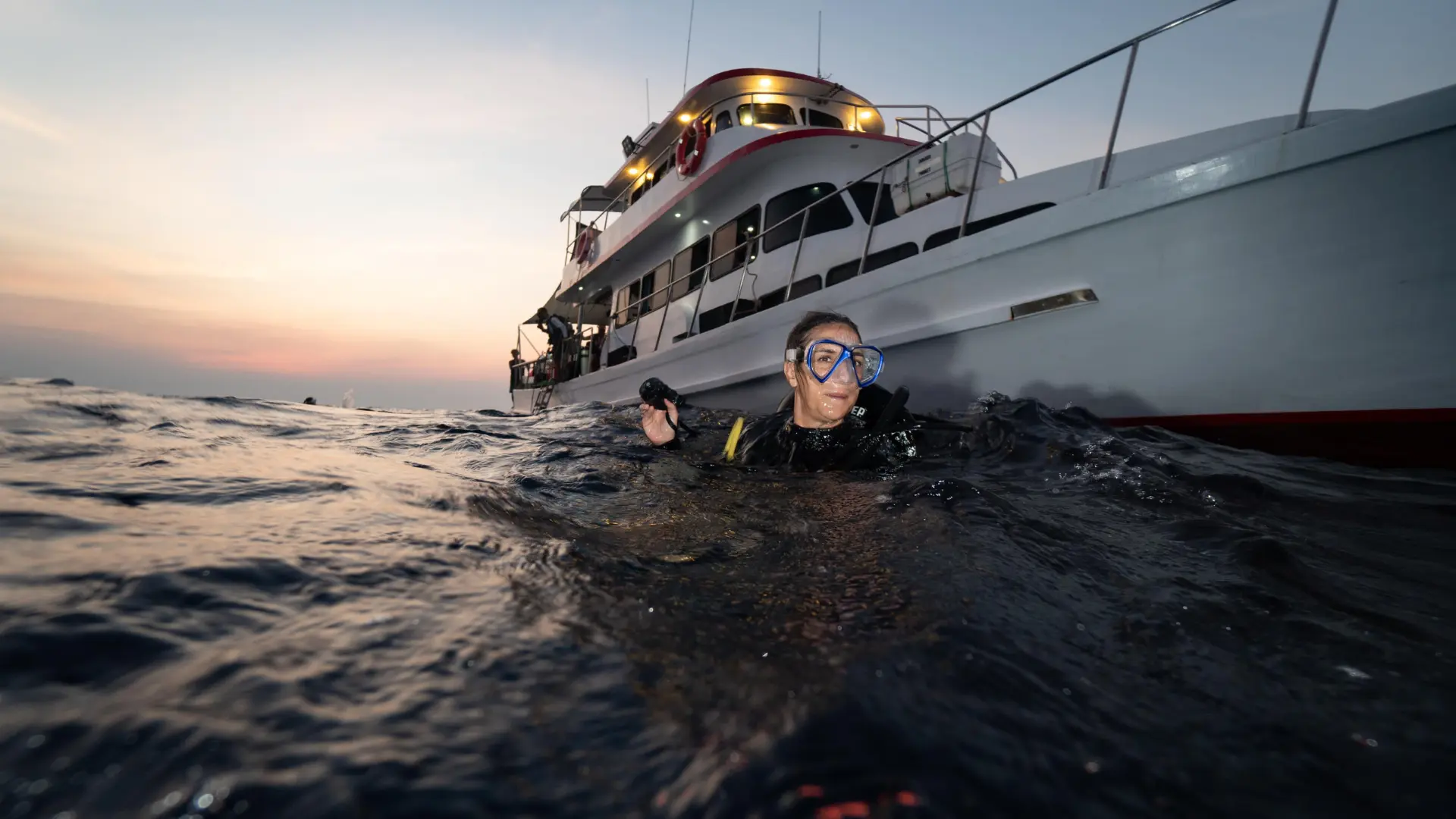 A woman scuba diver floating calmly at the water surface during a diving break.